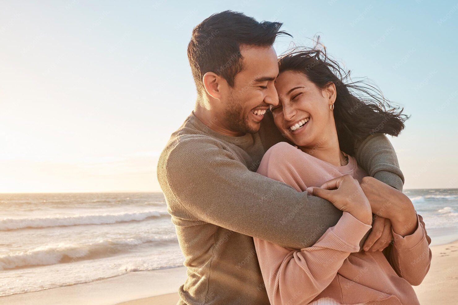Casal rindo abraçado na praia