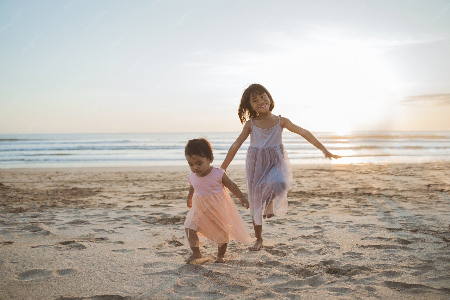 Duas meninas brincando e correndo na areia da praia