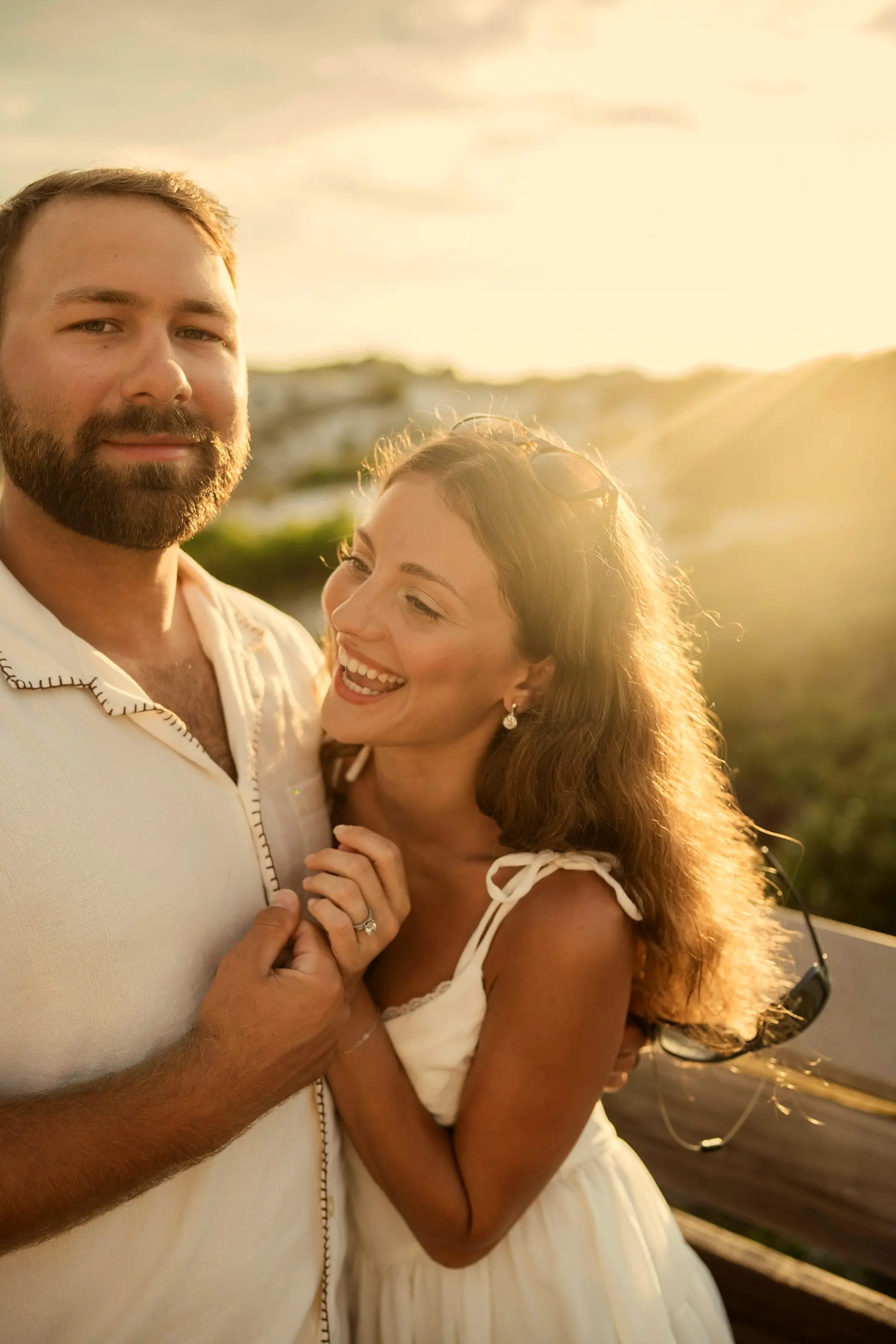 Casal rindo junto na luz dourada do fim de tarde à beira-mar