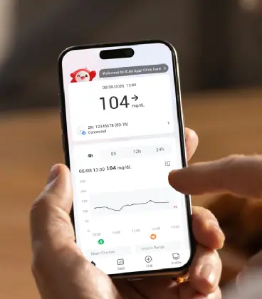 Mão segurando o celular com a tela do aplicativo iCan: 104 mg/dL e o gráfico das últimas horas